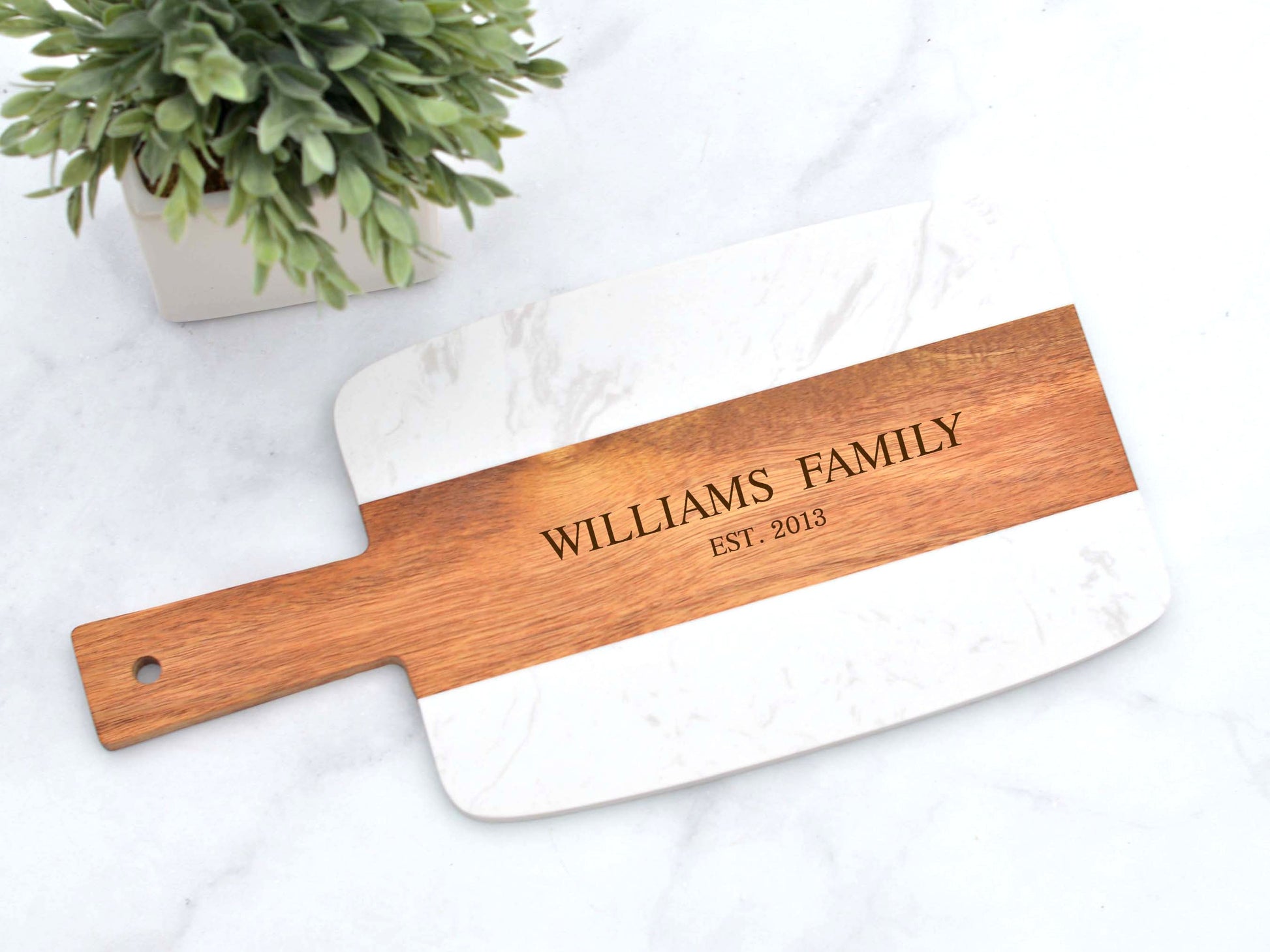 Rectangle charcuterie board with a handle, showcasing a beautiful combination of white marble stone and dark acacia wood with natural grains and textures. This board is perfect for serving meats, cheese, and fruits for an elegant presentation.